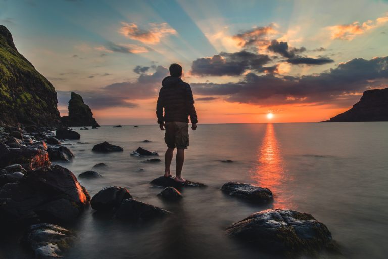 man looking at a sunrise on a beach